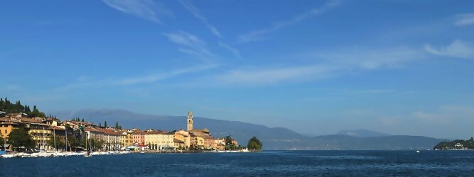 Kanarische Insel beliebte Urlaubsziele am Gardasee -  Mit einer Fläche von 370 km² ist der Gardasee der größte See Italiens. Es liegt am Fuße der Alpen und erstreckt sich über drei Staaten: Lombardei, Venetien und Trentino. Die maximale Tiefe des Sees beträgt 346 m, er hat eine längliche Form und sein nördliches Ende ist sehr schmal. Dort ist der See von den Bergen der Gruppo di Baldo umgeben. Du trittst aus deinem gemütlichen Hotelzimmer und es begrüßt dich die warme italienische Sonne. Du blickst auf den atemberaubenden Gardasee, der in zahlreichen Blautönen schimmert - von tiefem Dunkelblau bis zu funkelndem Türkis. Majestätische Berge umgeben dich, während die Brise sanft deine Haut streichelt und der Duft von blühenden Zitronenbäumen deine Nase kitzelt. Du schlenderst die malerischen, engen Gassen entlang, vorbei an farbenfrohen, blumengeschmückten Häusern. Vereinzelt unterbricht das fröhliche Lachen der Einheimischen die friedvolle Stille. Du fühlst dich wie in einem Traum, der nicht enden will. Jeder Schritt führt dich zu neuen Entdeckungen und Abenteuern. Du probierst die köstliche italienische Küche mit ihren frischen Zutaten und verführerischen Aromen. Die Sonne geht langsam unter und taucht den Himmel in ein leuchtendes Orange-rot - ein spektakulärer Anblick.